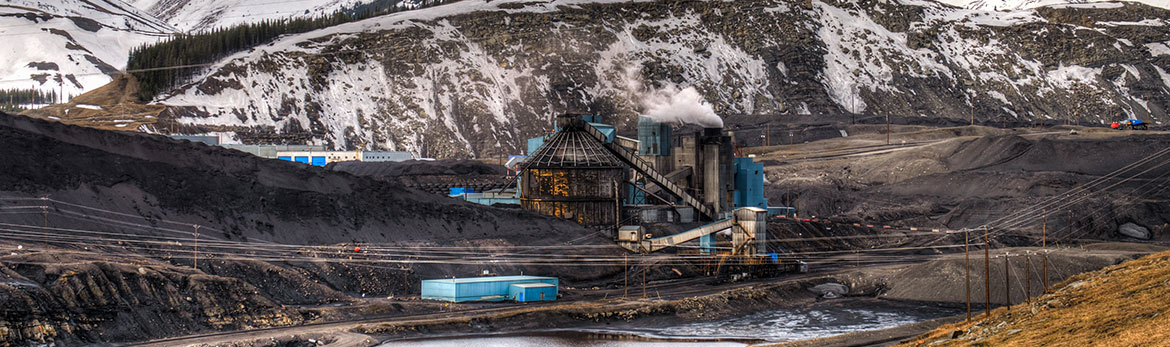 Photo of a mining operation in the foreground with mountains in the background