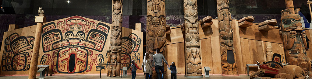 Photo de la Grande Galerie au Musée canadien de l’histoire montrant des œuvres d’art, des artefacts, des sculptures et des mâts totémiques autochtones