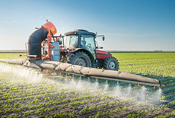 Photo of a tractor spraying a farm field