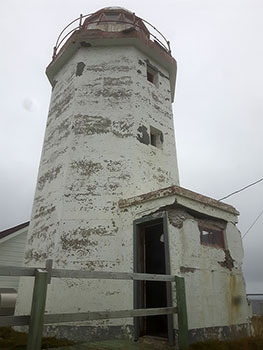 Exterior photo of the Green Island Lighthouse, and its damaged exterior, in Catalina, Newfoundland and Labrador