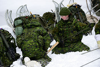 Photo of two Army Reserve soldiers working together during a training exercise in the snow to prepare soldiers for combat and non-combat operations