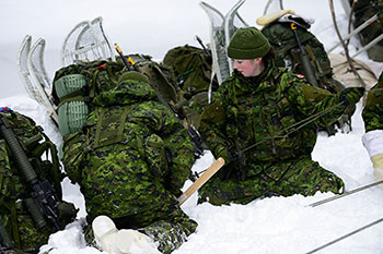 Photo de deux soldats de la Réserve de l’Armée qui travaillent ensemble pendant une séance d’entraînement dans la neige afin de préparer les soldats à des opérations de combat et à des opérations sans combat