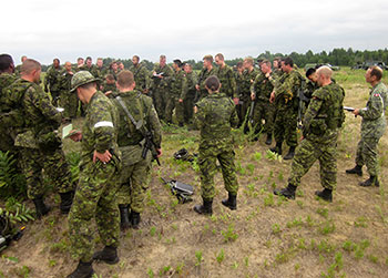 Photo of Regular Army soldiers instructing and coaching Army Reserve soldiers during a training exercise on tactics and skills at Canadian Forces Base Petawawa